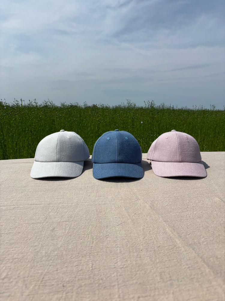 photo de trois casquettes en lin dans un champs de lin en Normandie pendant le rouissage