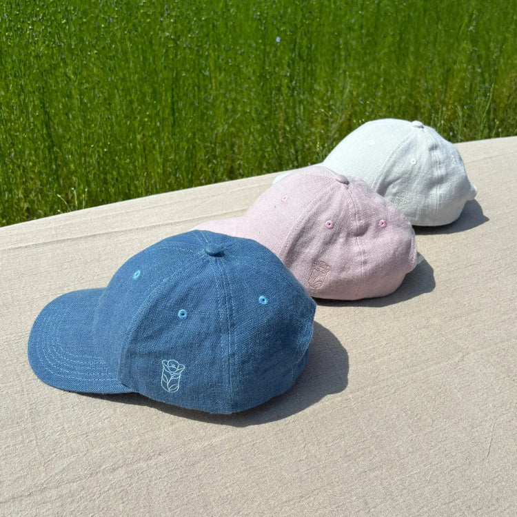 photo de trois casquettes en lin dans un champs de lin en Normandie pendant le rouissage